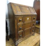 Mid 20th Century oak bureau having three drawers with knob handles on bun feet, 39ins high x 30ins