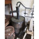 Cast iron water pump mounted on a large wooden barrel