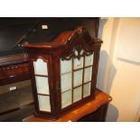 Small mahogany wall cabinet having central bar glazed door enclosing shelved interior, 26ins high,