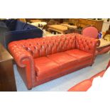 Pair of 20th Century red buttoned leather upholstered three seat chesterfield sofas raised on low