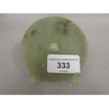 Chinese carved pale green jade disc on a display stand