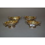 Set of four George III London silver two handled pedestal salts having embossed floral decoration,