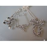 Pair of silver necklaces together with a bow form paste set brooch