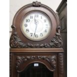 Early 20th Century Continental oak longcase clock with carved decoration, the circular silvered dial