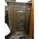 George III oak hanging corner cabinet, the single rectangular panelled door with later carved