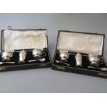 Two Birmingham silver three piece condiment sets with spoons, each in a fitted case