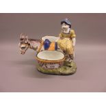 French Faience figure of a girl riding a donkey carrying two baskets