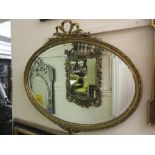 Oval gilt framed bevelled edge wall mirror with bow surmount together with another gilt framed
