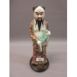 Chinese porcelain enamel decorated figure of a standing sage on hardwood stand, 10.5ins high