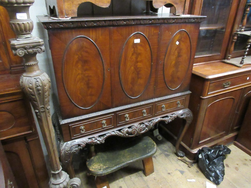 Reproduction mahogany cocktail cabinet with oval panelled doors above three drawers raised on carved