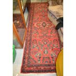 Sarouk style runner with all-over floral design on a red ground with borders, 112ins x 40ins