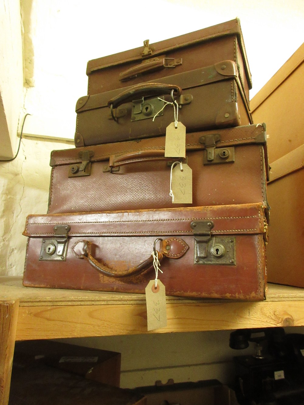 Early 20th Century leather suitcase, together with three smaller simulated leather suitcases