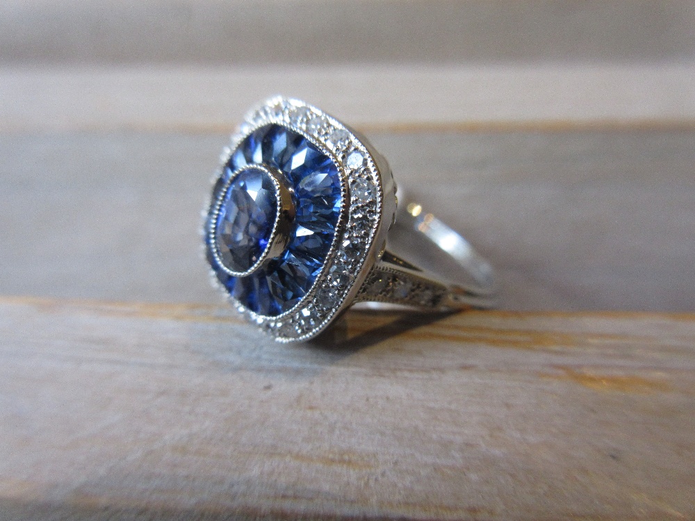 Platinum ring set central sapphire bordered by calibre cut sapphires and diamonds