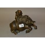 Gold and brown patinated bronze group of a man seated on a water buffalo