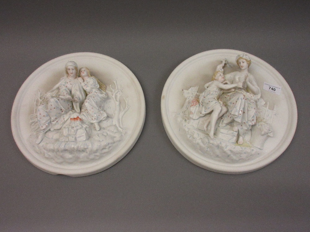 Pair of Continental circular bisque wall plaques decorated in high relief with figures (one at