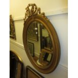 Edwardian oval wall mirror with bow surmount, moulded frame and bevelled plate, 41ins high, 30ins