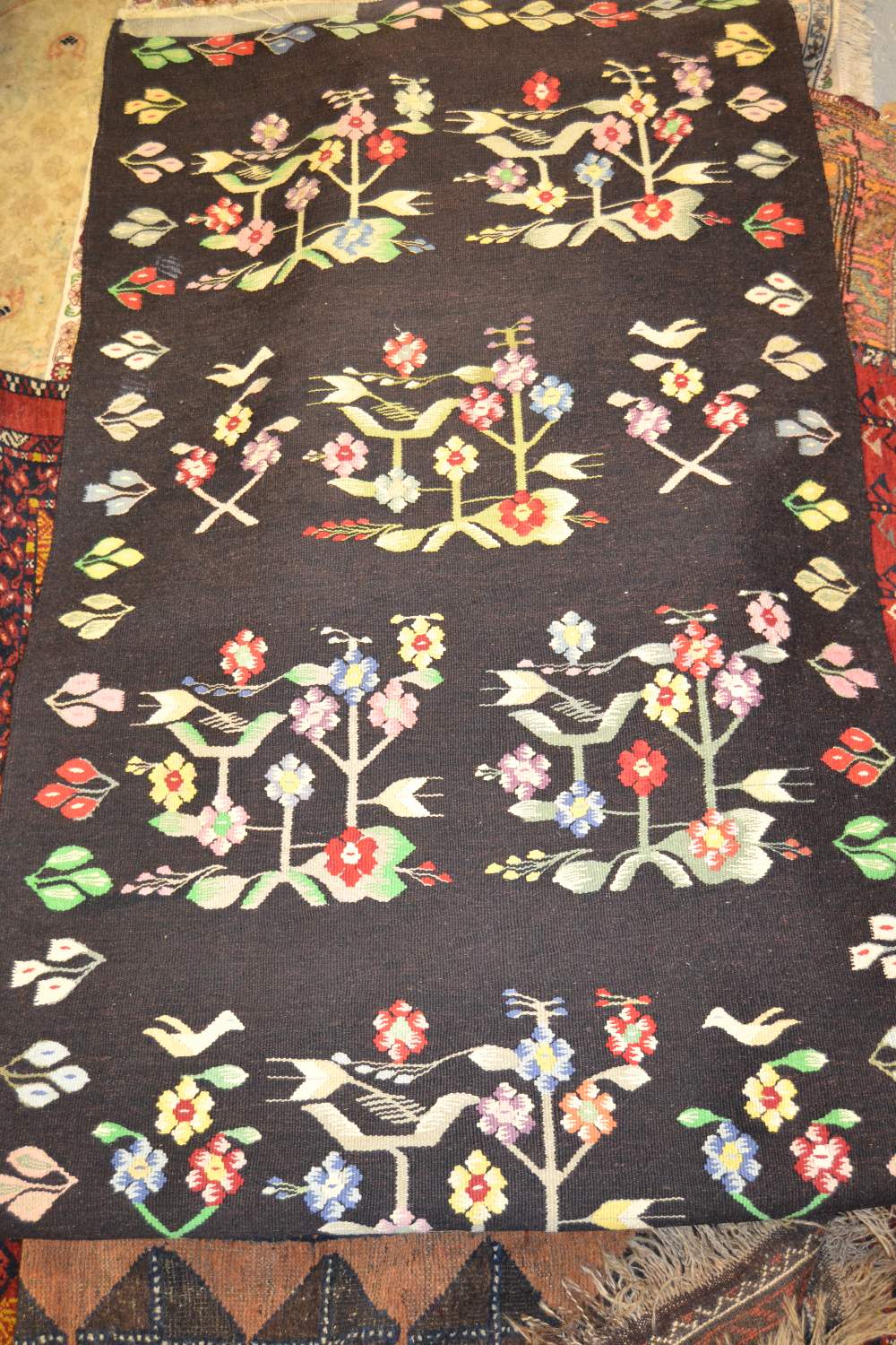 Kelim rug of floral design on black ground, together with another Kelim rug on blue ground Black