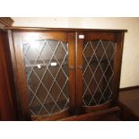 Late 20th Century oak bookcase having adjustable shelves and two leaded glazed doors on a shaped