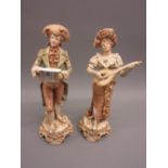 Pair of Royal Dux matt glazed and gilded figures of boy and girl musicians, 12ins high