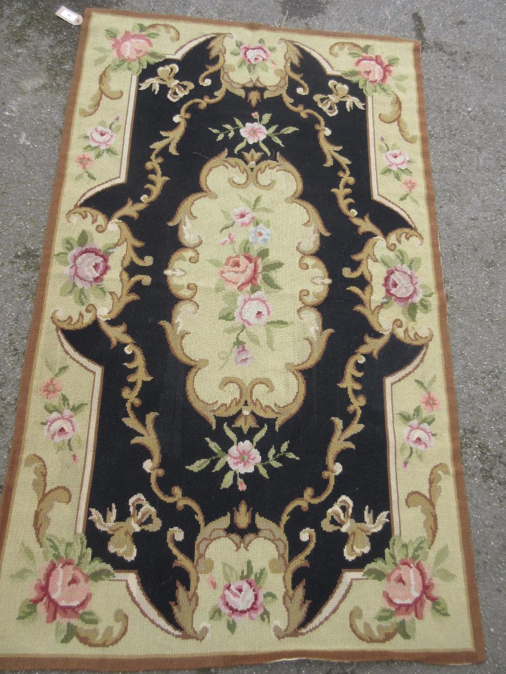 Small Aubusson type needlepoint rug with floral design on a black ground, 59ins x 36ins