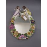 Sitzendorf floral encrusted table mirror surmounted by figures of cherubs, 11ins high