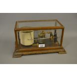 F. Darton and Co. gilt brass barograph housed in an oak and glazed cabinet