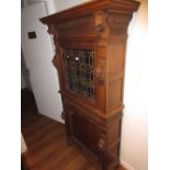 19th Century oak side cabinet, the moulded and carved cornice above a single leaded coloured glass
