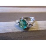 18ct White gold ring set oval emerald flanked by two brilliant cut diamonds