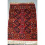 Small Afghan rug with a repeating gol design on red ground, 71cms x 54cms