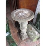 Weathered cast concrete bird bath in the form of putto supporting a cornucopia