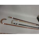 Two silver mounted walking sticks, another with white metal mount and a swagger stick