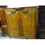 19th Century French low pine armoire, the frieze carved with a basket of flowers above two carved
