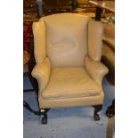 Early 20th Century cream leather upholstered wing back armchair, raised on cabriole claw and ball