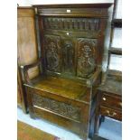 Antique oak settle with a carved panel back above a box seat and carved panel front, 19th Century