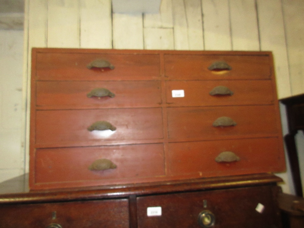 19th Century red painted pine bank of eight drawers having cast iron cup handles, 17ins high x 33ins