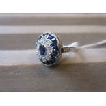 Platinum ring set central oval sapphire surrounded by diamonds and calibre cut sapphires