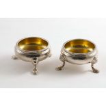 A PAIR OF GEORGE II SQUAT CIRCULAR SALTS on three legs with gilt interiors and ropework rims, by