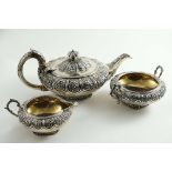 A MATCHED THREE-PIECE TEA SET of squat circular form with chased floral work around the upper