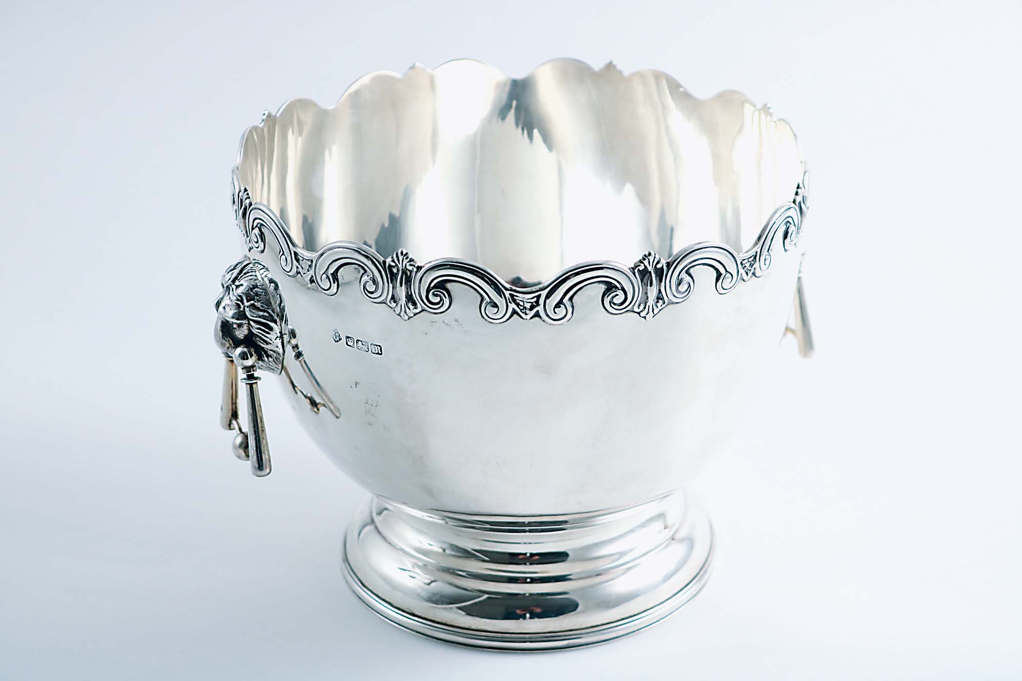 AN EDWARDIAN ROSE BOWL with a wavy scroll rim, a domed circular foot and twin, lion mask & drop