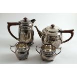 AN ARTS & CRAFTS MATCHED FOUR-PIECE TEA SET with hammered circular bodies, a frieze of applied