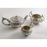 A GEORGE III / IV EMBOSSED THREE-PIECE TEA SET with squat circular bodies, decorative feet and