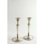 A PAIR OF GEORGE III CANDLESTICKS on circular bases with plain, tapering columns, urn-shaped