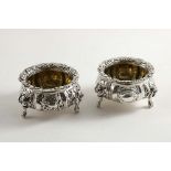 A PAIR OF GEORGE IV EMBOSSED SALTS of shaped circular outline with cast, fruiting feet, chased