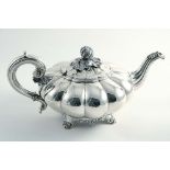 A GEORGE IV MELON-FLUTED TEA POT on decorative scroll feet, with a c-scroll handle and a fruit