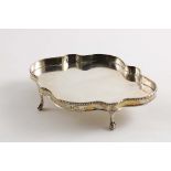 A GEORGE III TEA POT STAND of shaped oval outline on ball & claw feet with a bead border and
