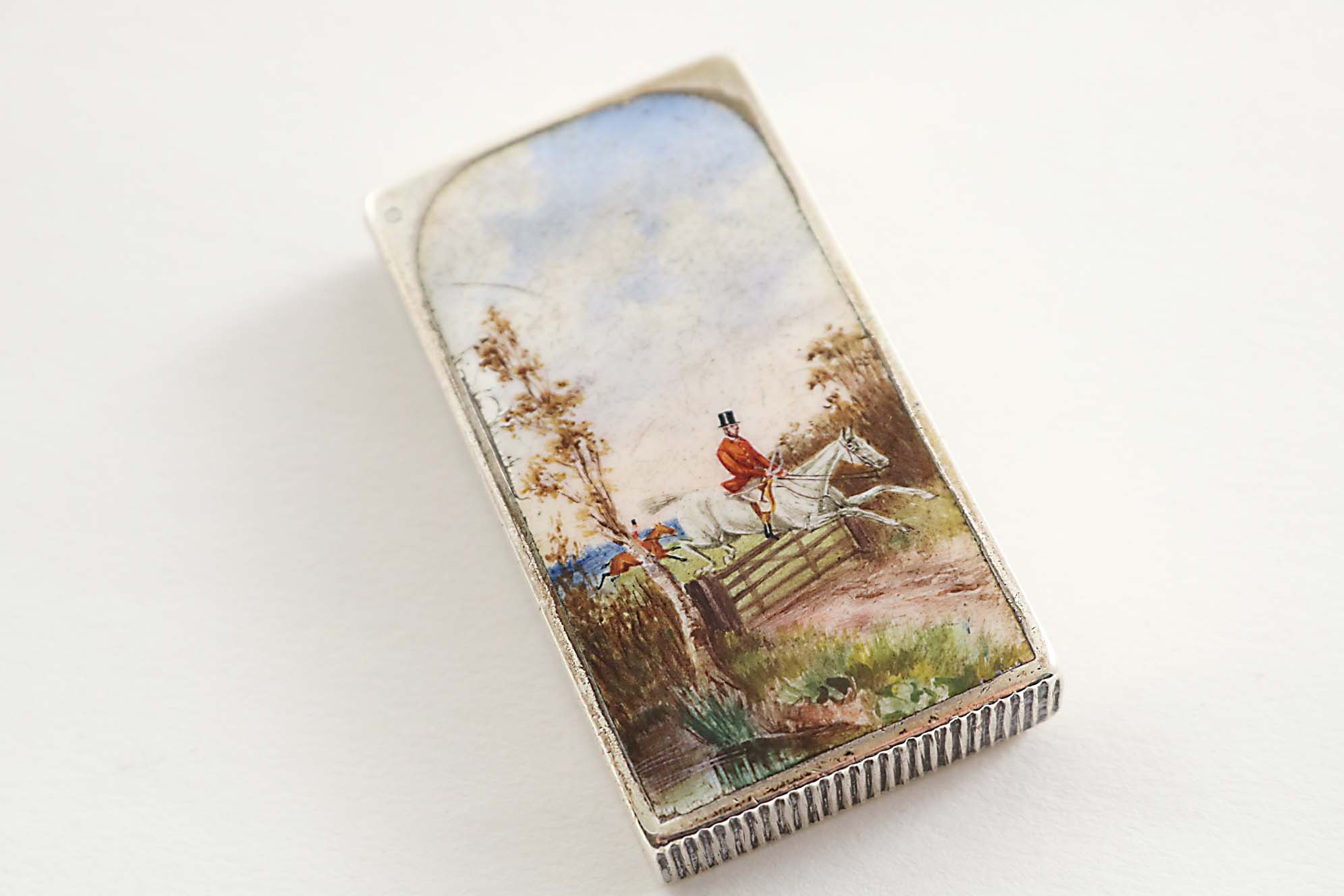 A VICTORIAN RECTANGULAR VESTA CASE with a flip cover, enamelled on the front with a huntsman on a