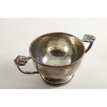 A SMALL EARLY 20TH CENTURY CUP OR BOWL with a hammered finish and twin curved handles with cast