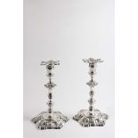 A PAIR OF GEORGE II CAST CANDLESTICKS on shaped circular bases with shell decoration with knopped