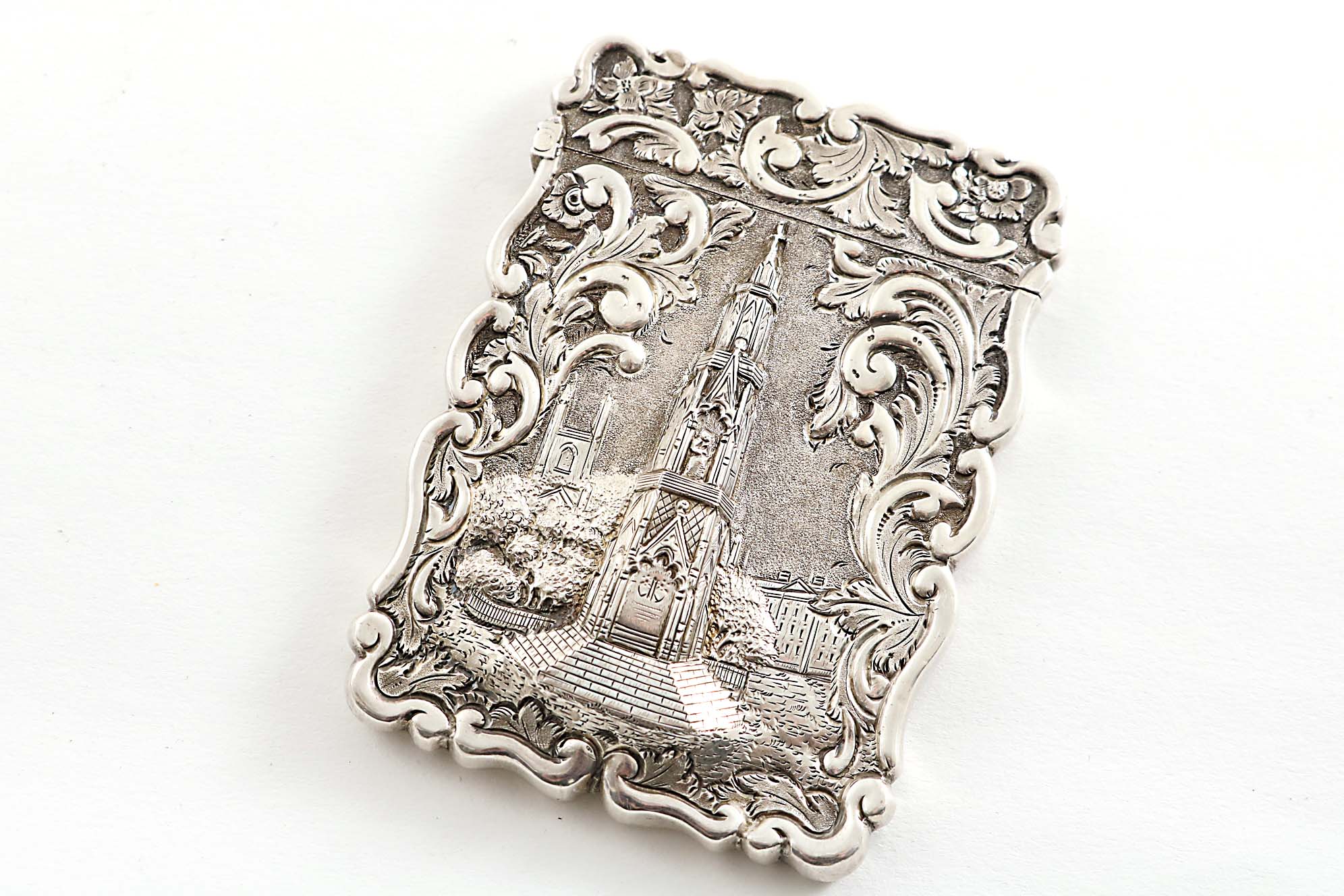 A VICTORIAN EMBOSSED "CASTLE TOP" CARD CASE of shaped rectangular outline with a scroll border & a