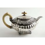 A GEORGE IV FLUTED OVAL TEA POT with shell & scroll feet, a decorative border and an ivory c-